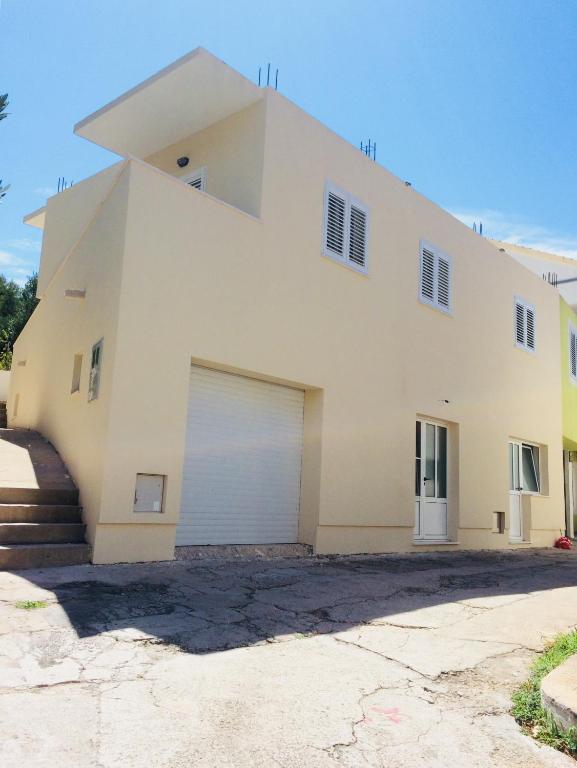 a large white house with a garage at Apartmani Kronjac in Milna