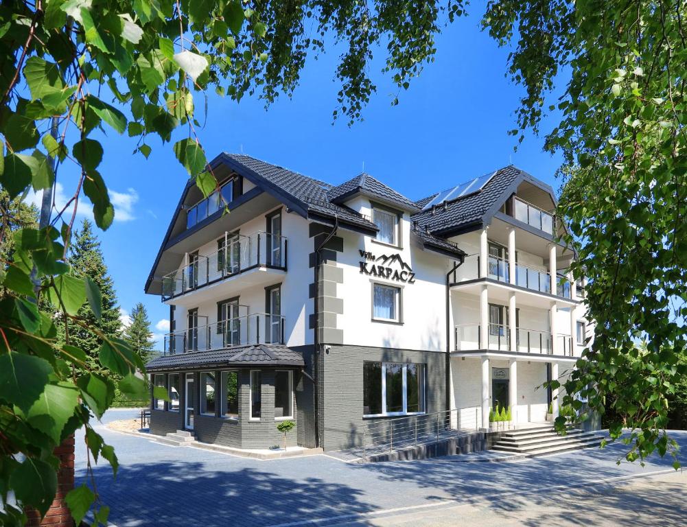 un grand bâtiment blanc avec un toit noir dans l'établissement Villa Karpacz, à Karpacz