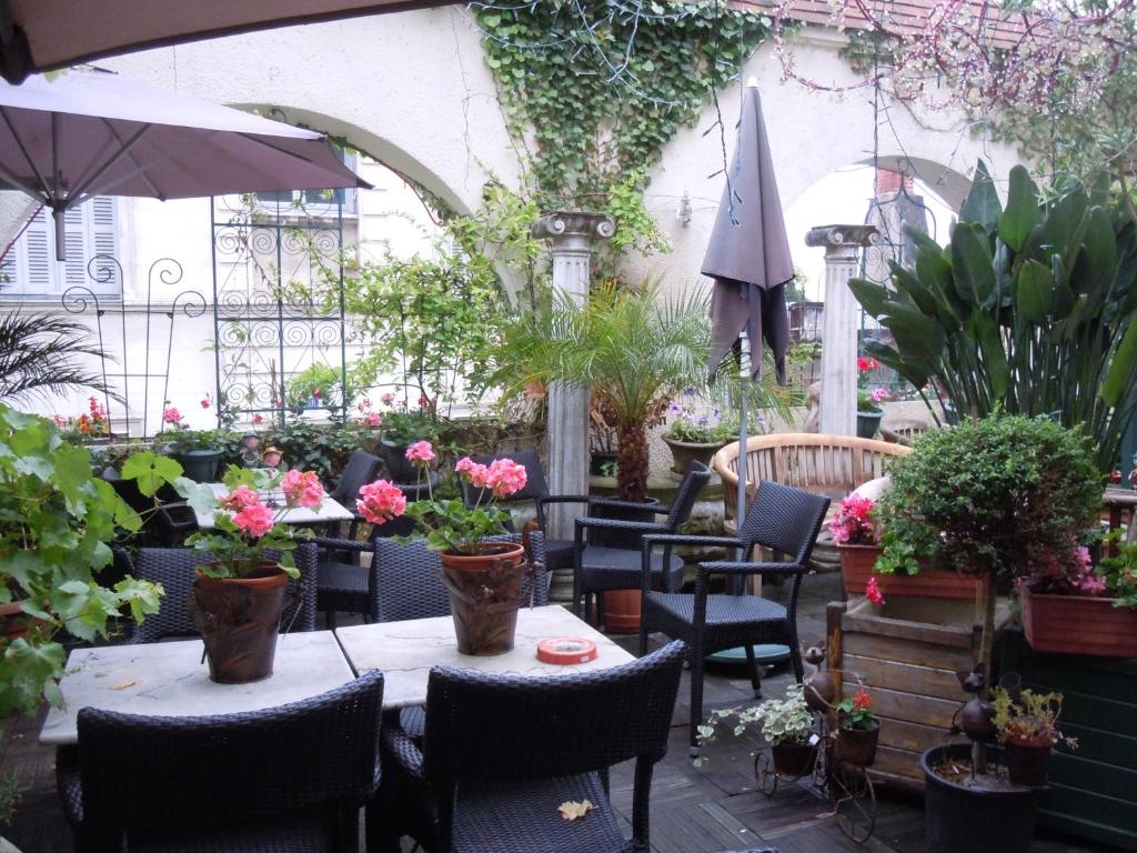 un patio con mesas y sillas con flores y plantas en La Croix Blanche, en Montrichard