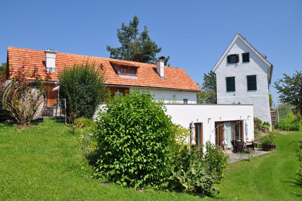 ロイトシャッハにあるBio-Weingut Leitnerのオレンジ色の屋根と庭のある白い家