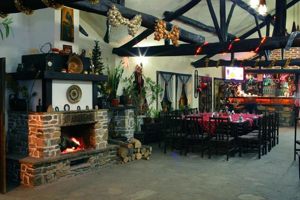 a restaurant with a fireplace and a table and chairs at Hotel Divetsite in Sliven