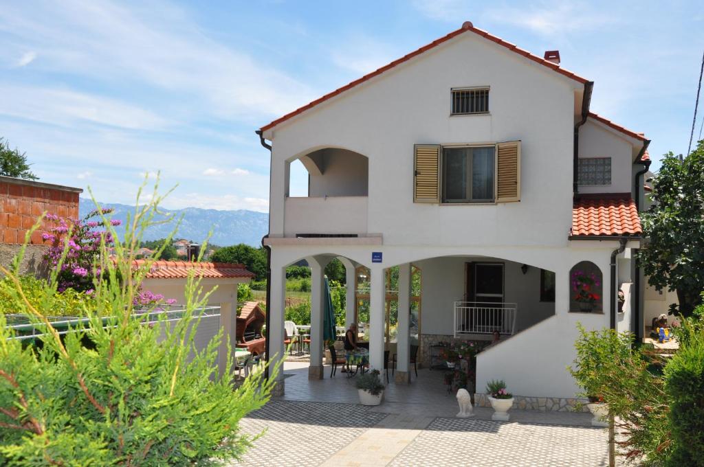 a white house with a porch and a patio at Apartments Alicia Lopar-50m vom Strand in Lopar