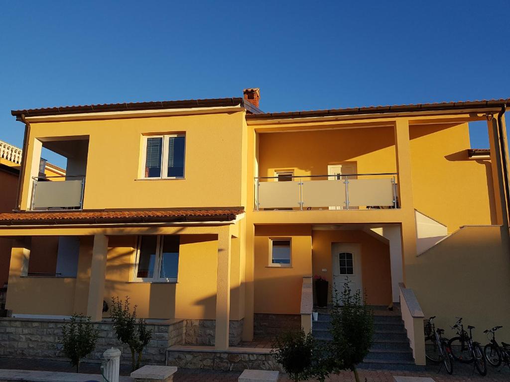 a yellow house with stairs and a balcony at Apartments Lean in Poreč
