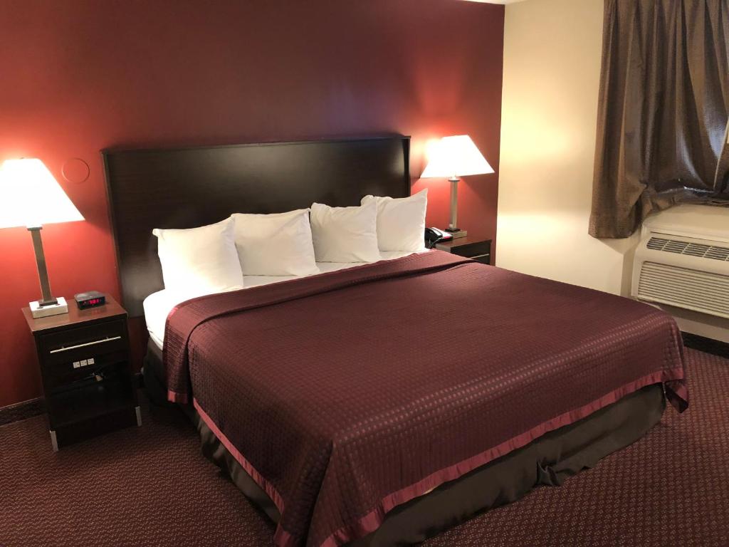 a large bed in a hotel room with two lamps at Regal Inn Chicago O'Hare - Franklin Park in Franklin Park