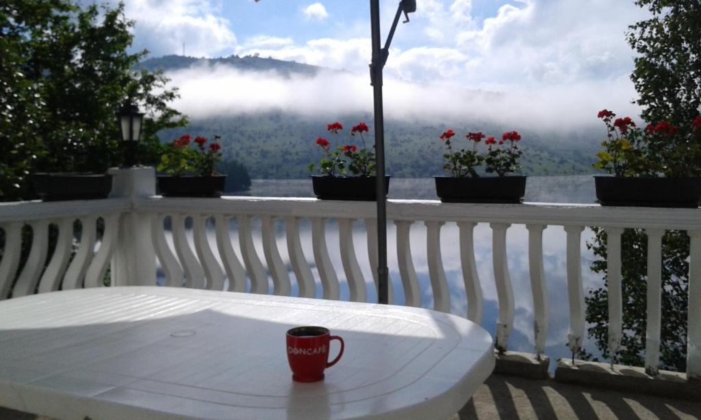 a coffee cup sitting on a white table on a balcony at Uvacko jezero (Uvac Lake) in Nova Varoš