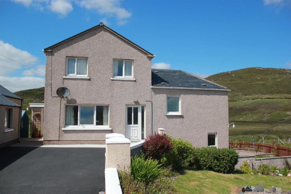a house with a hill in the background at 73 Westend, Balallan, Isle of Lewis in Balallan