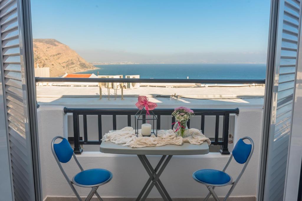 einen Tisch und Stühle auf einem Balkon mit Meerblick in der Unterkunft Antigoni in Agia Galini