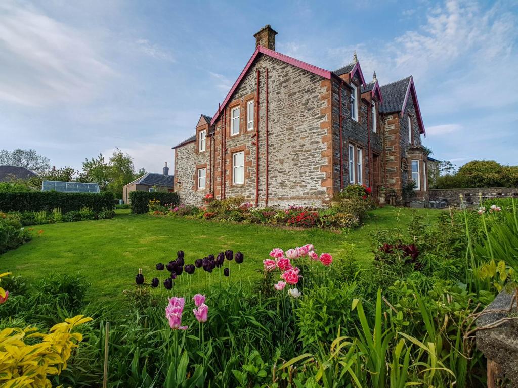 an old brick house with flowers in the yard at Drumfearne Guesthouse & Tearoom in Carradale