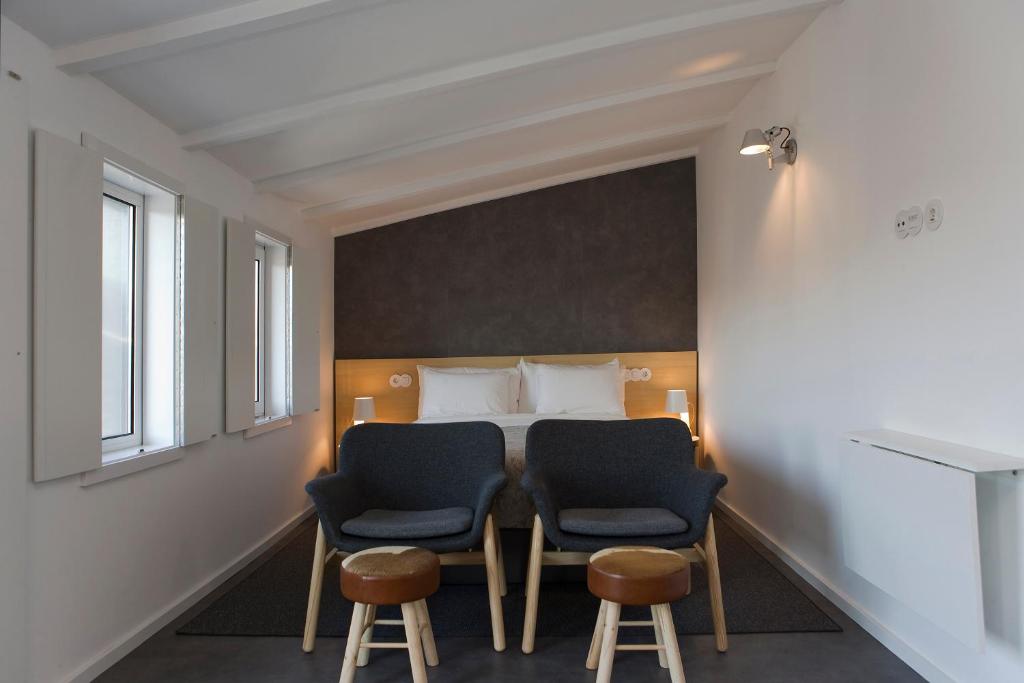 ポルトにあるOporto Design Attic - Solar da Avenidaの椅子2脚とベッド1台が備わる客室です。