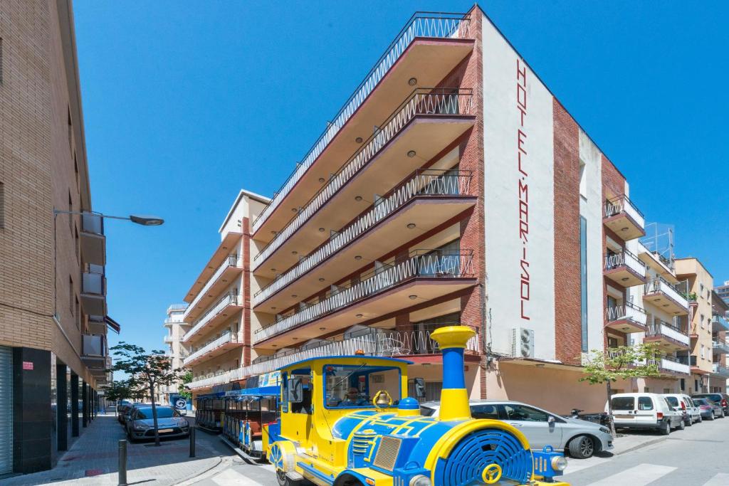 a yellow and blue train parked in front of a building at Hotel Mar i Sol in Calella