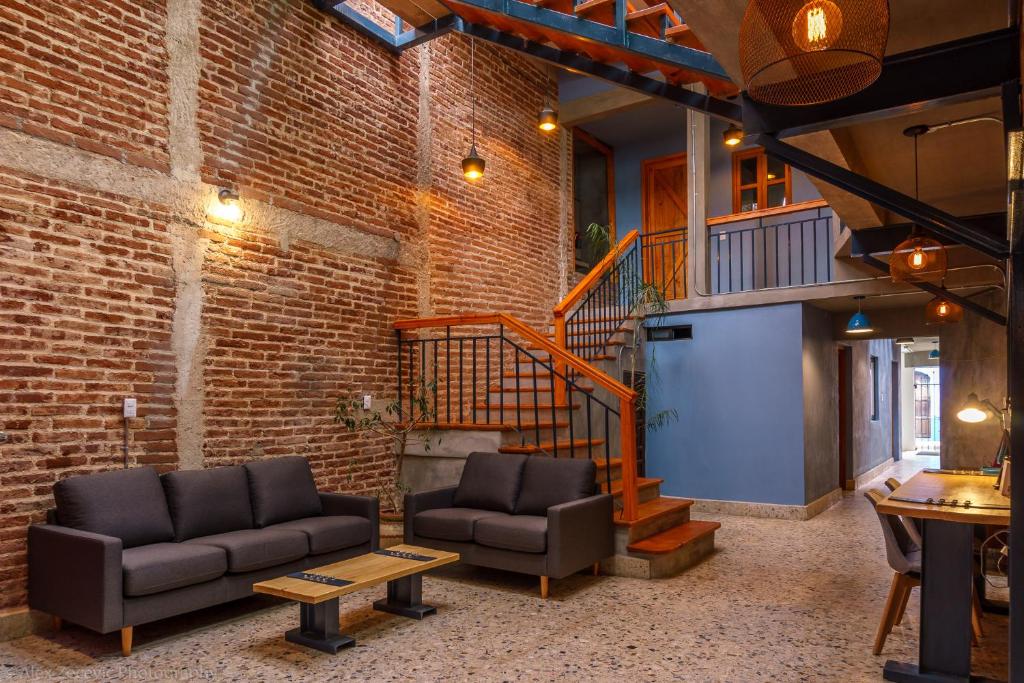 a living room with two couches and a brick wall at La Abuelita Hostal in San Cristóbal de Las Casas