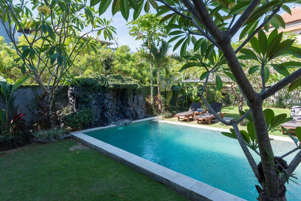 a swimming pool in the yard of a house at Koming Guest House in Canggu
