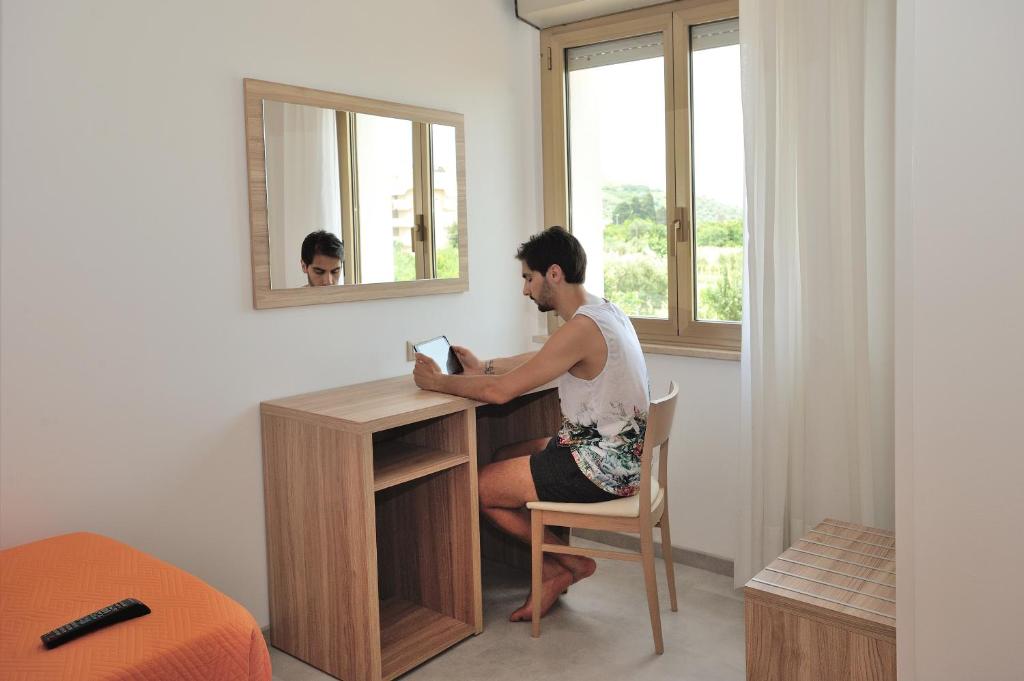 a man sitting at a desk in front of a mirror at Hotel Lidia in Alba Adriatica