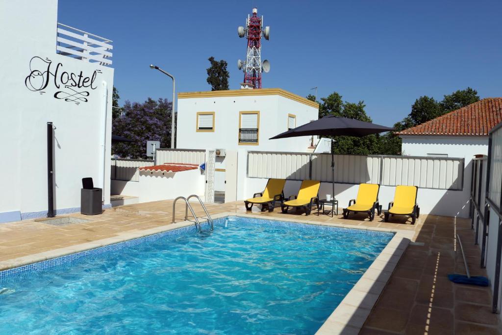a swimming pool with yellow chairs next to a building at In My House in Castro Verde