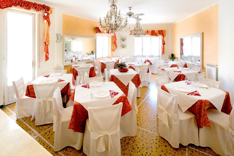 una sala da pranzo con tavoli bianchi e sedie bianche di Hotel Gabbiano ad Alassio