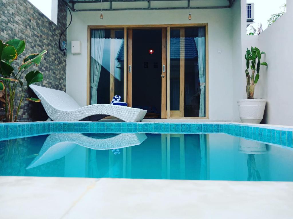 a house with a swimming pool with a chair and a table at Dragonfly Hostel and Homestay in Nusa Penida