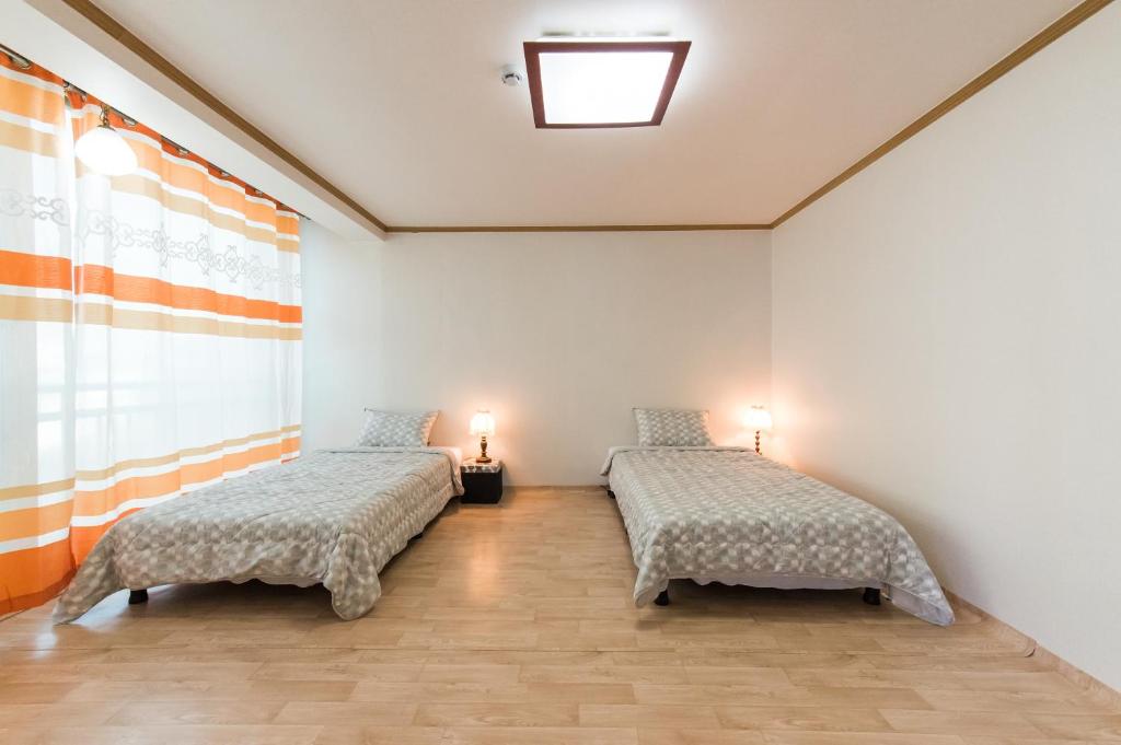 two beds in a white room with two lamps at Casa Cielo in Seoul