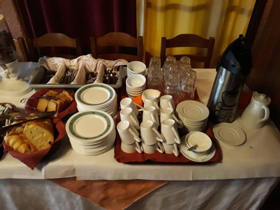 een tafel met witte borden en bekers en een dienblad met eten bij Sintrivanis Mountain in Áno Skotína