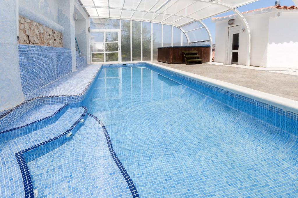 a large swimming pool with blue tiles in a building at Llumicel in Ador
