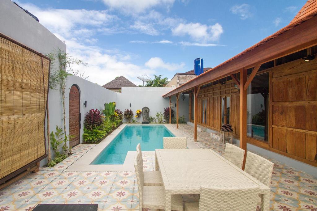 a patio with a table and chairs next to a swimming pool at Villa Joglo Jagat in Seminyak