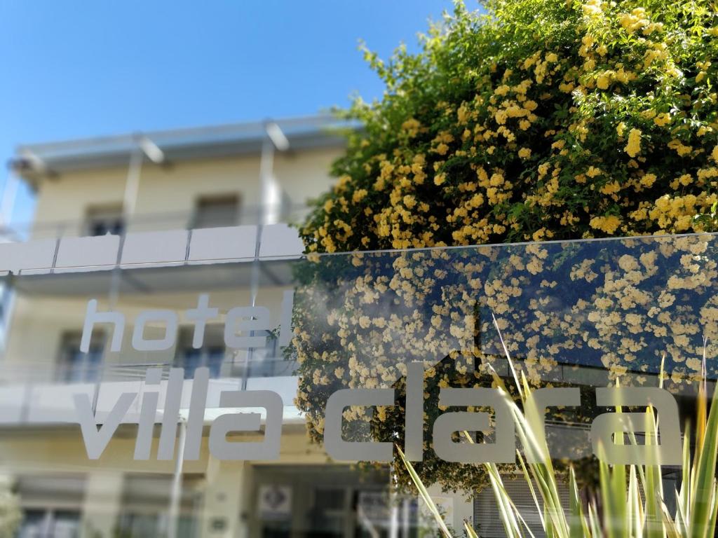 a sign in front of a building with flowers at Hotel Villa Clara in Nago-Torbole