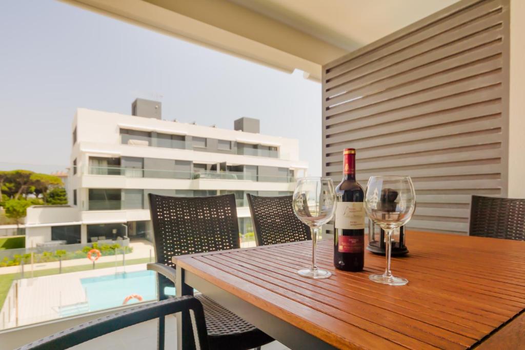 een fles wijn en twee glazen op een houten tafel bij Apartamentos Bahía Blanca in El Puerto de Santa María