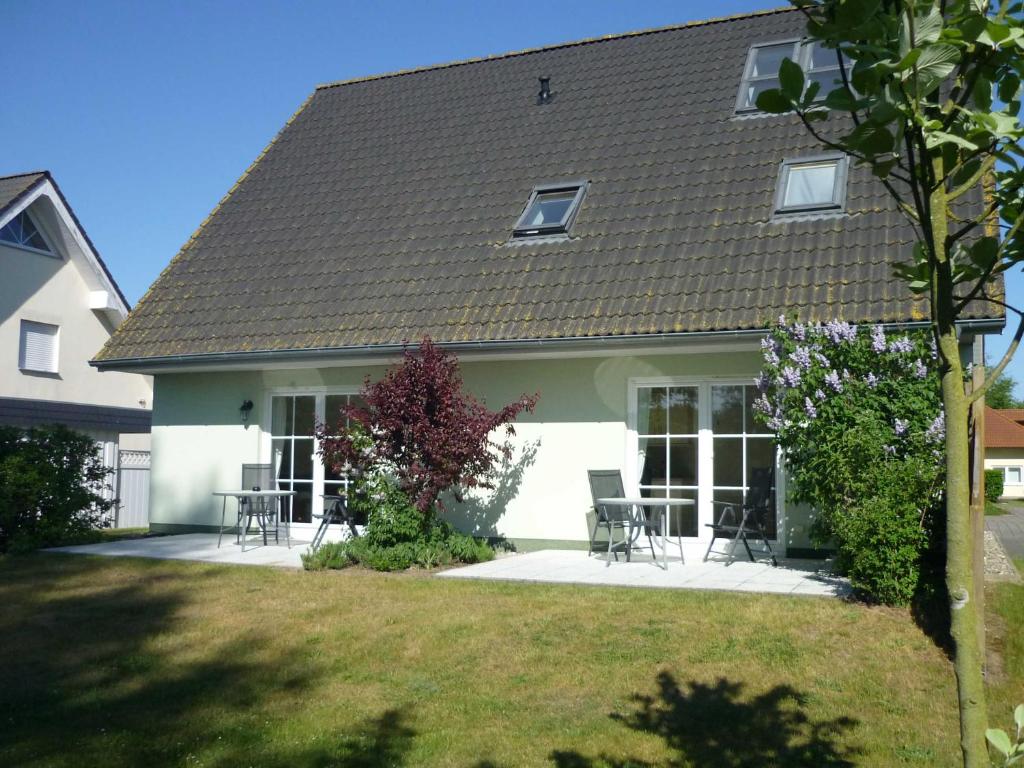 a house with chairs and tables in a yard at Fewo Wiesenblick_MEYH in Ostseebad Karlshagen