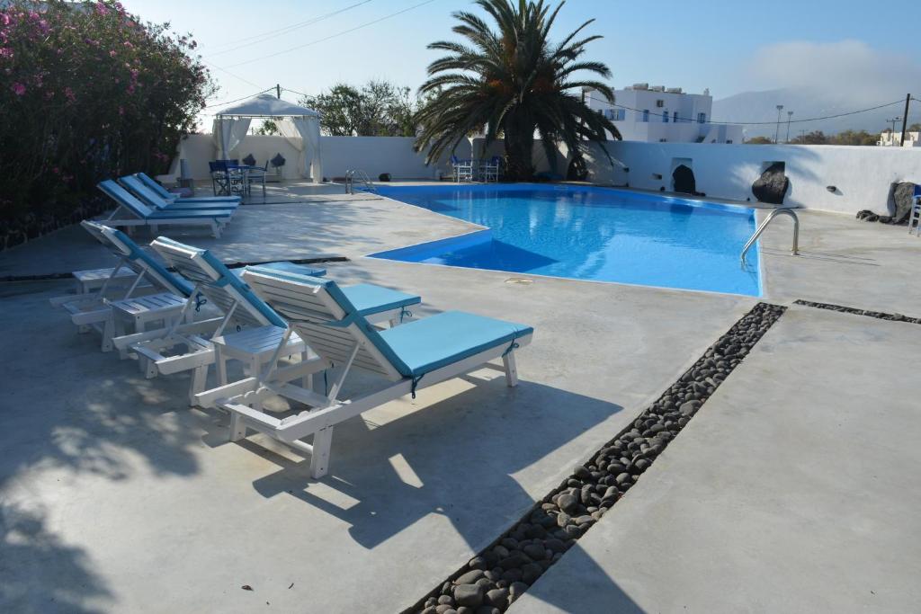uma piscina com duas cadeiras e uma mesa e uma piscina em Melina Hotel em Fira