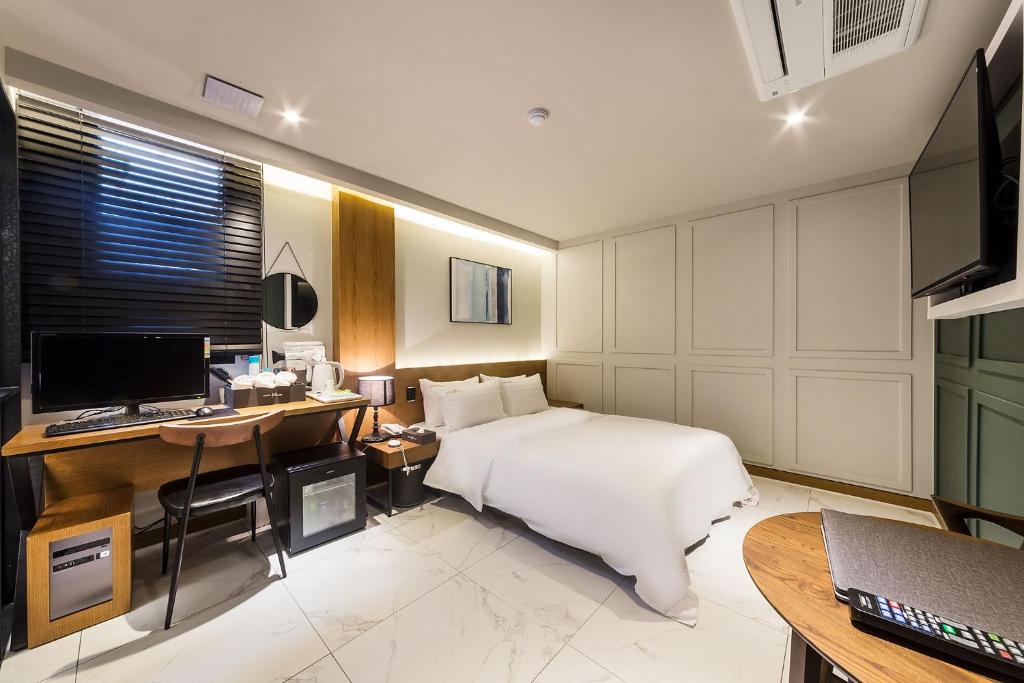 Schlafzimmer mit einem Bett, einem Schreibtisch und einem Computer in der Unterkunft Plum Hotel in Siheung