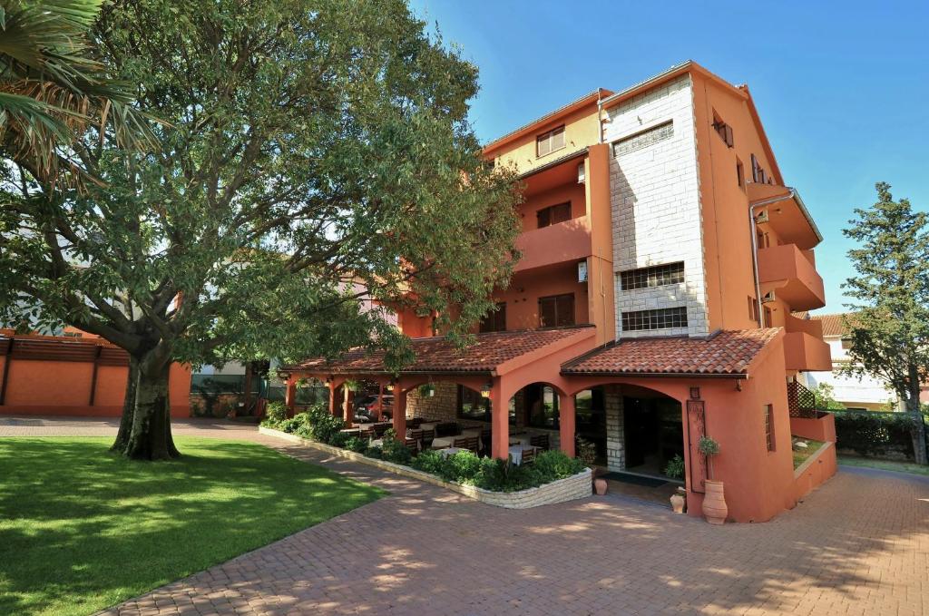 un bâtiment orange avec un arbre devant lui dans l'établissement Villa Maimare, à Biograd na Moru