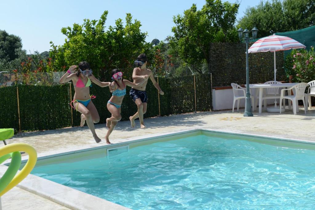 three girls jumping into a swimming pool at villa la Scaletta in Alghero