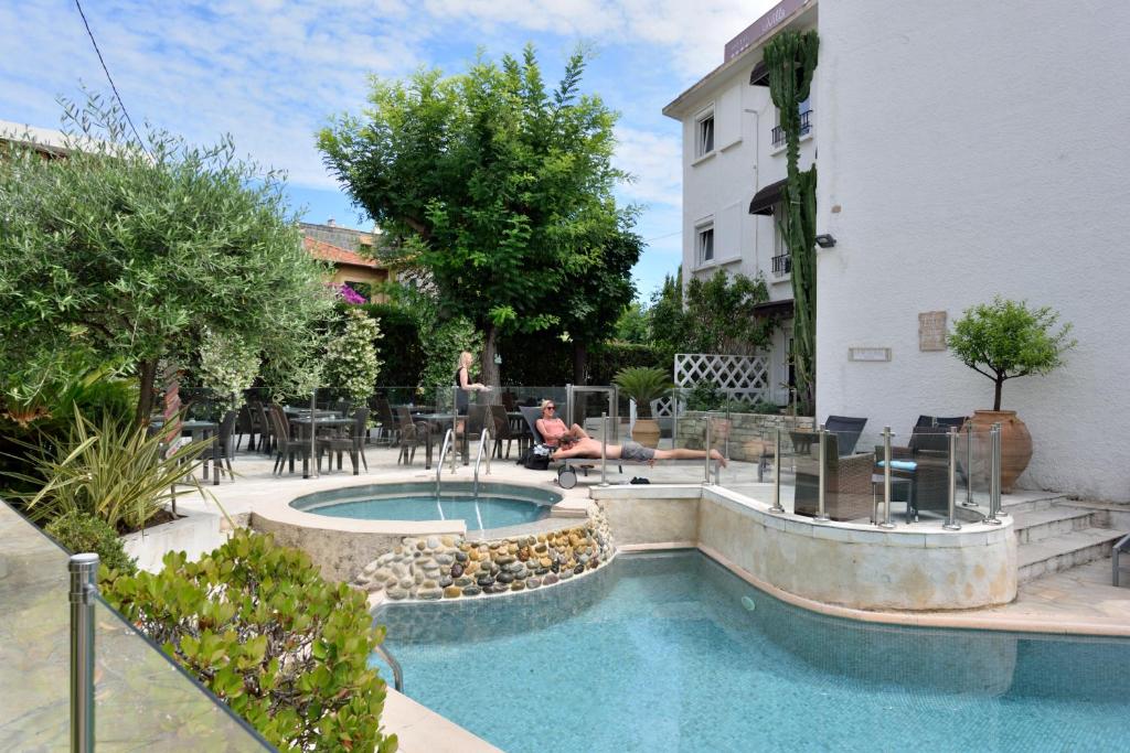 a person laying on a patio next to a swimming pool at Hôtel La Villa Cannes in Cannes