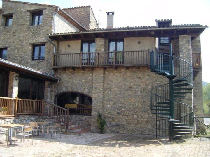a large brick building with a staircase in front of it at Hostal de la Rovira in Oix