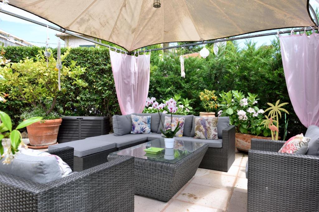an outdoor patio with wicker furniture and an umbrella at Hôtel La Villa Cannes in Cannes