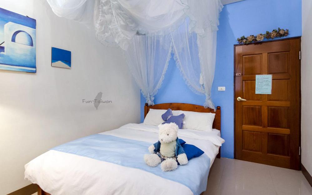 a teddy bear sitting on a bed in a bedroom at sweet home B&amp;B in Hualien City