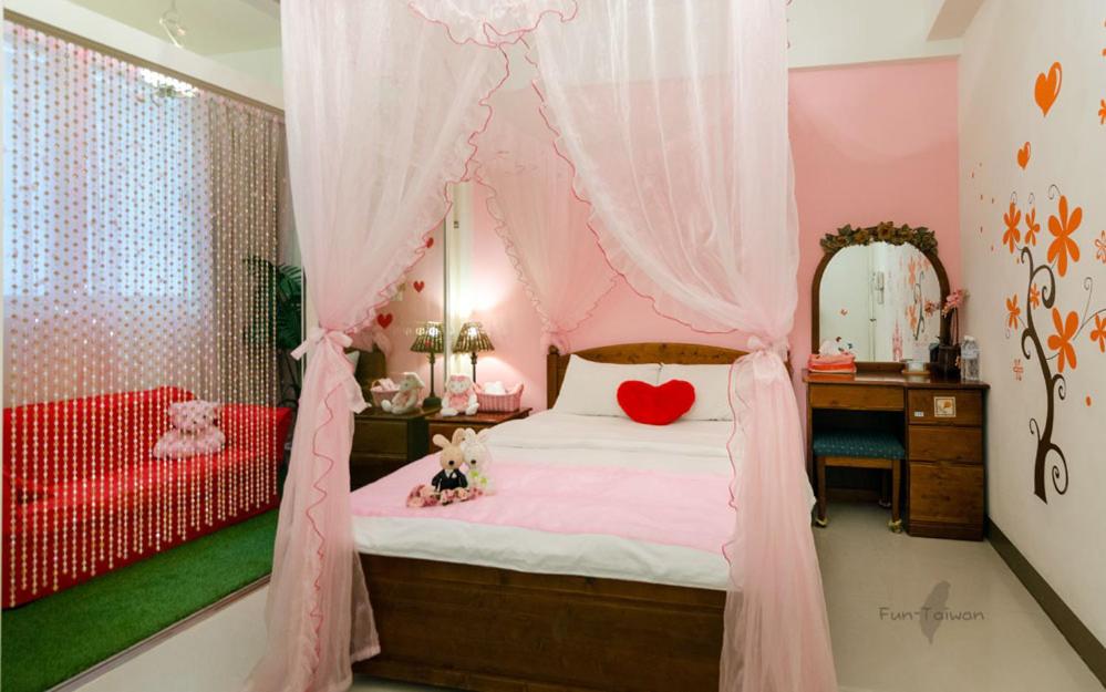 a bedroom with a bed with a heart pillow on it at sweet home B&amp;B in Hualien City