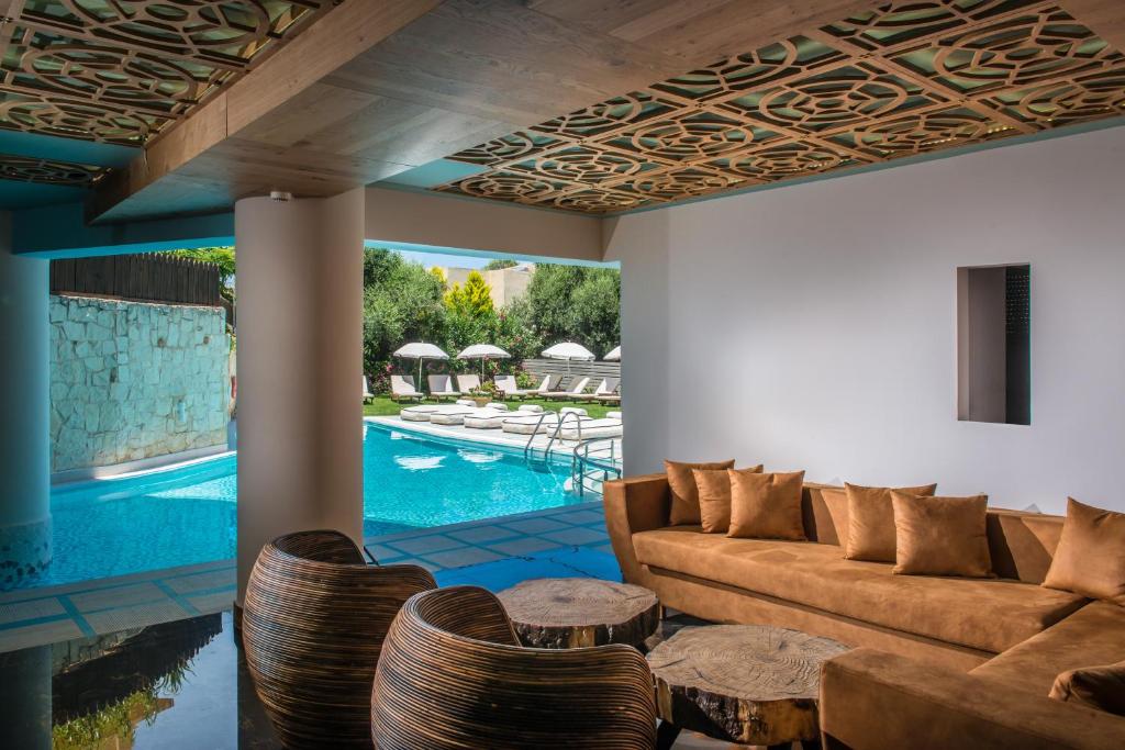 een woonkamer met een bank en stoelen en een zwembad bij Anesis Blue Boutique Hotel in Chersonissos