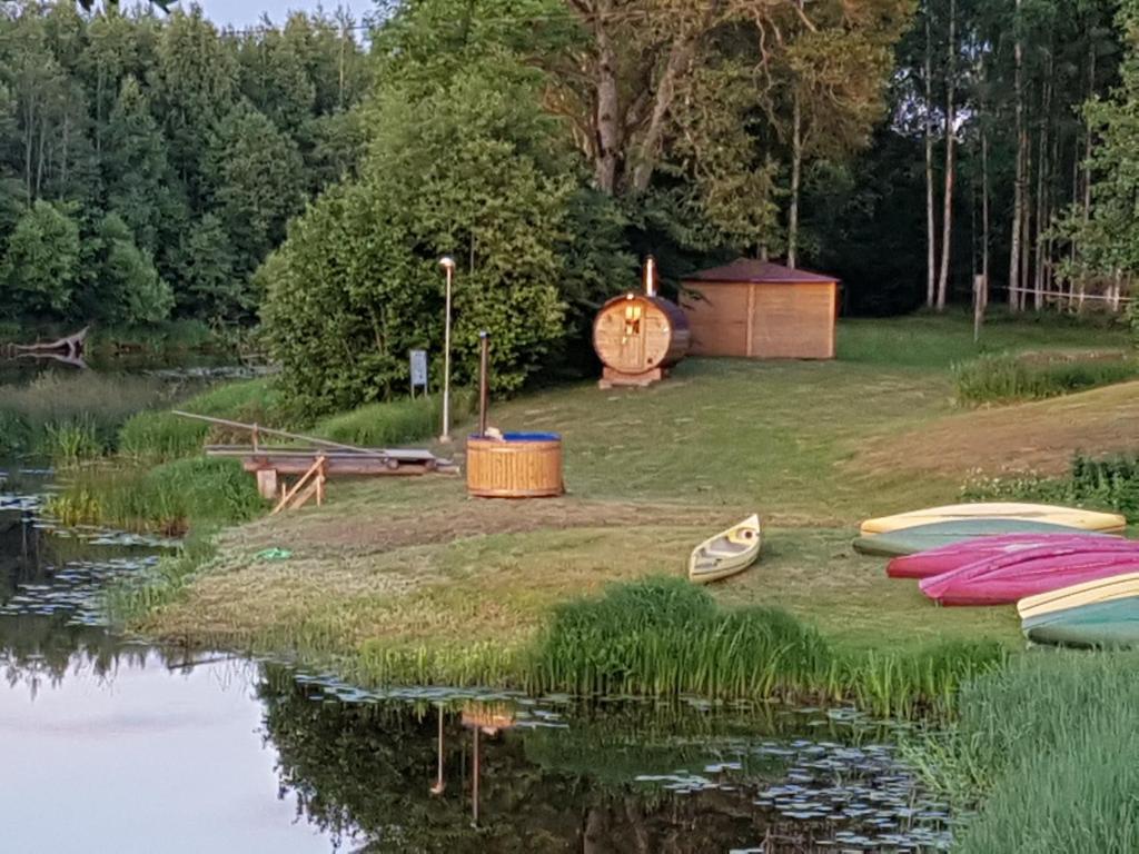 eine Gruppe von Booten, die auf dem Gras neben einem See sitzen in der Unterkunft Soomaa Water Camp in Jõesuu