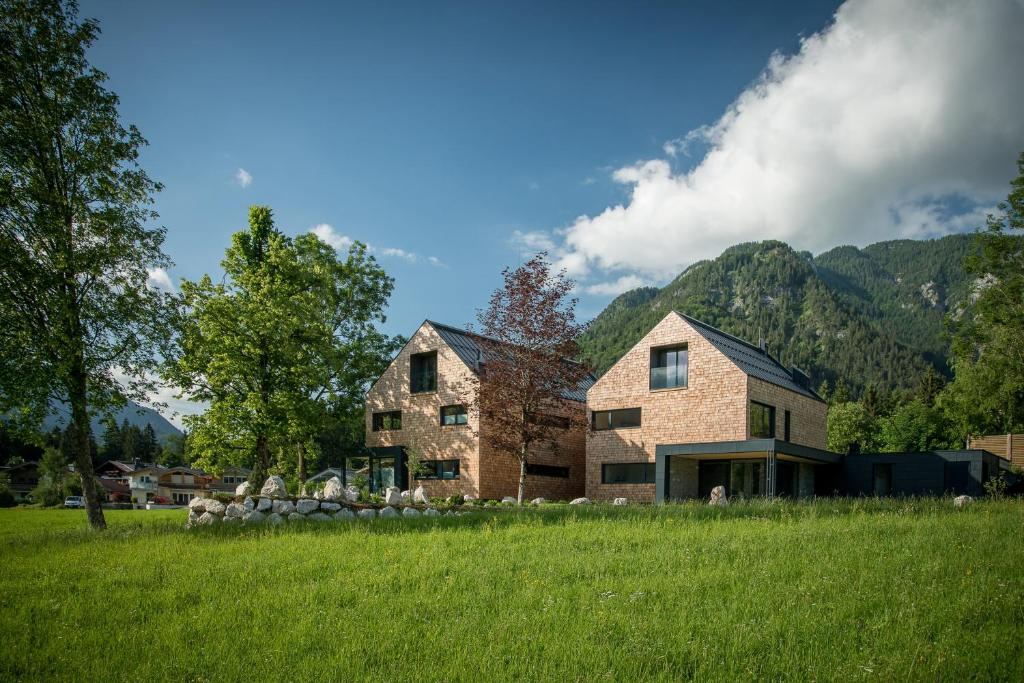 ein Haus auf einem Feld mit Bergen im Hintergrund in der Unterkunft pure mountain BASE in Erpfendorf