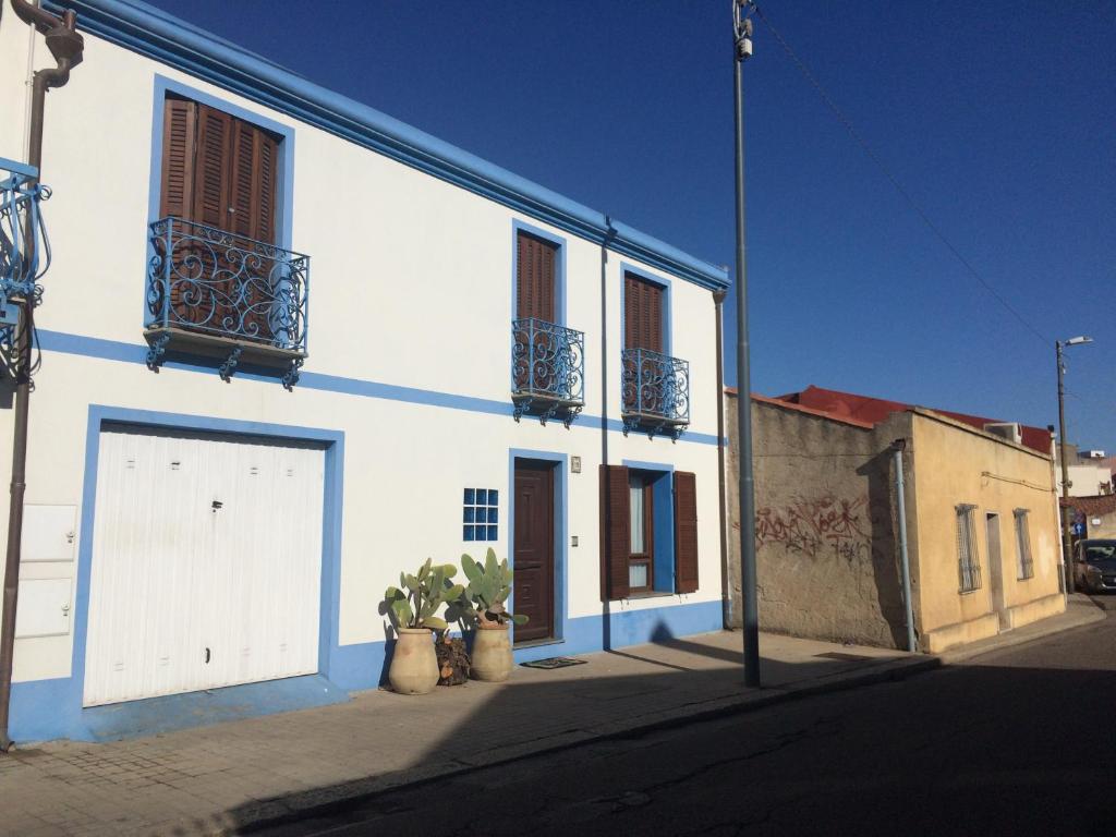 a white building with two doors and potted plants on a street at L'Onda in Oristano