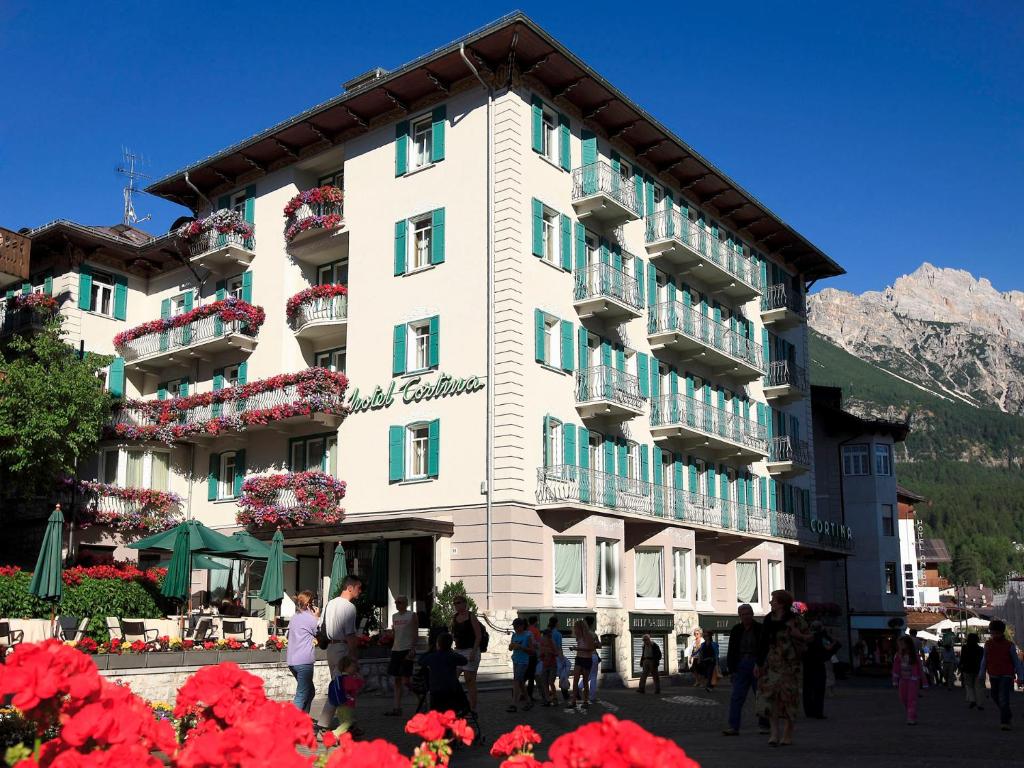 a large white building with flowers in front of it at Hotel Cortina in Cortina dʼAmpezzo