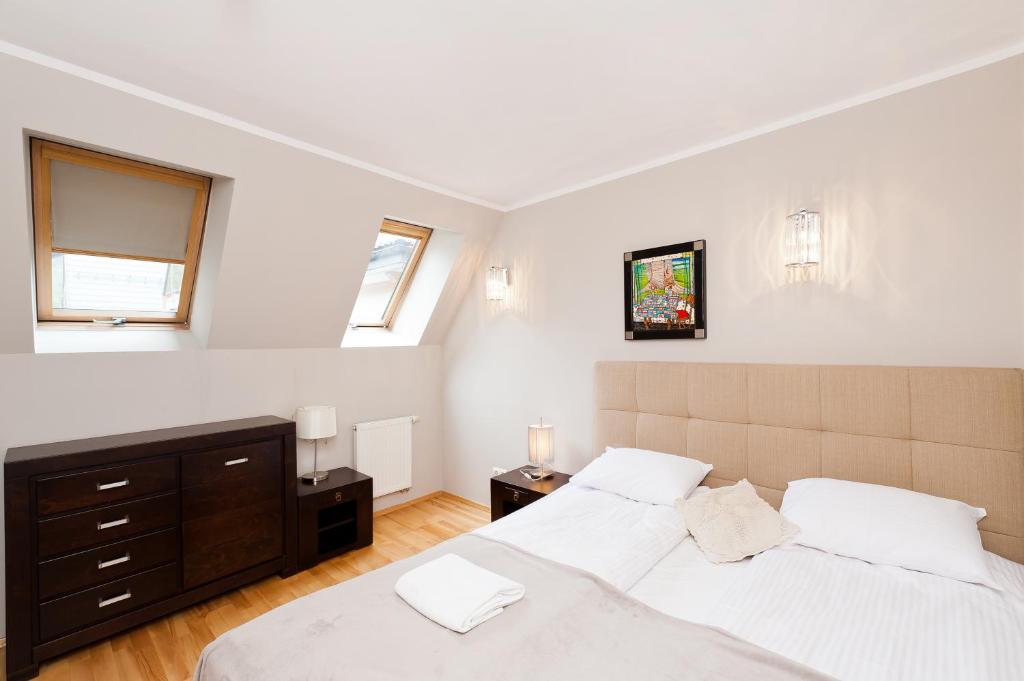 two beds in a bedroom with two windows at Apartamenty Sun & Snow Centrum in Zakopane