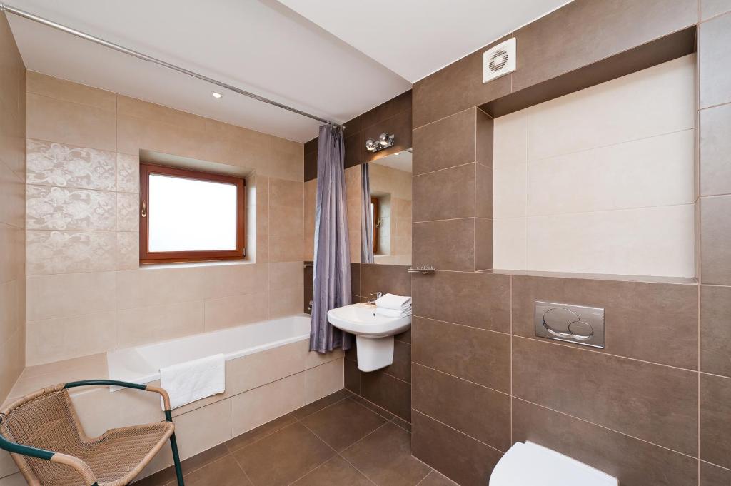 a bathroom with a sink and a toilet and a tub at Apartamenty Sun & Snow Centrum in Zakopane