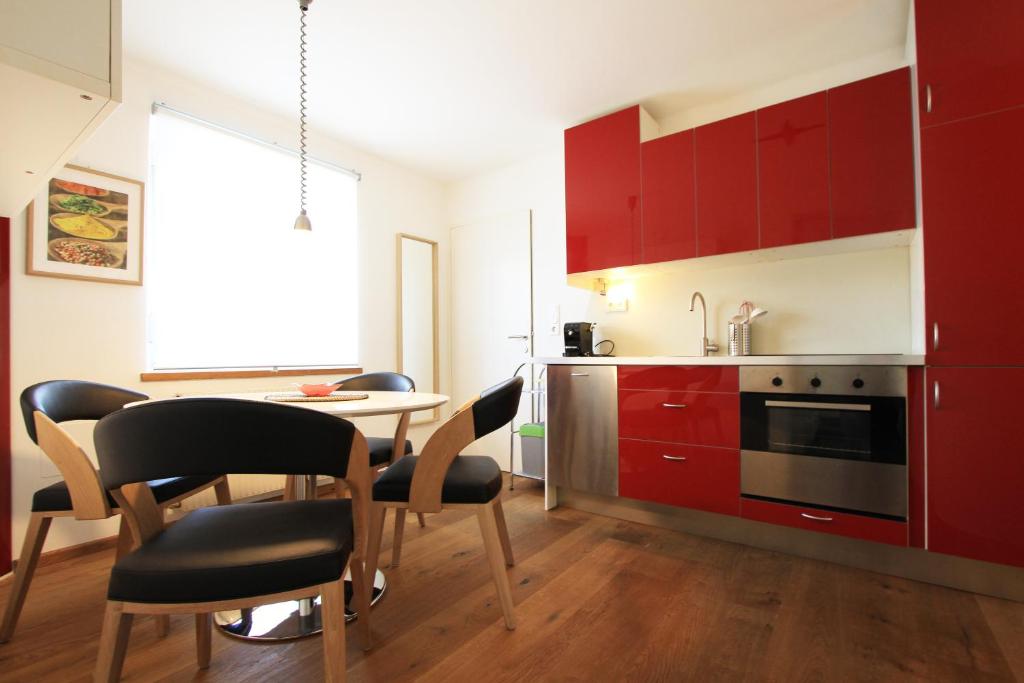 a kitchen with red cabinets and a table and chairs at Ferienwohnungen „am Schlosspark Tamsweg“ im UNESCO Biosphärenpark Lungau in Tamsweg