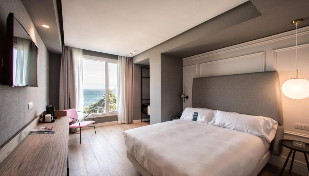 a bedroom with a large bed and a large window at Hotel Riazor in A Coruña