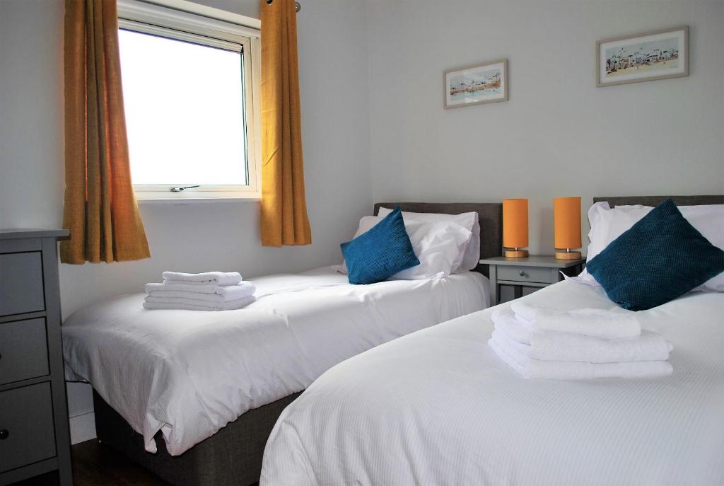 two beds in a room with a window at For the Shore, Fistral Beach Newquay - 2 Bed 2 bath - Private Parking with garage for 2 vehicles in Newquay