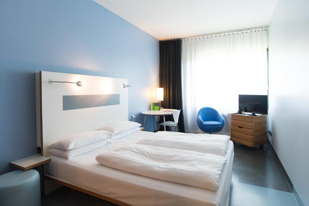 ein Schlafzimmer mit einem weißen Bett und einem blauen Stuhl in der Unterkunft Ku'Damm 101 Hotel in Berlin