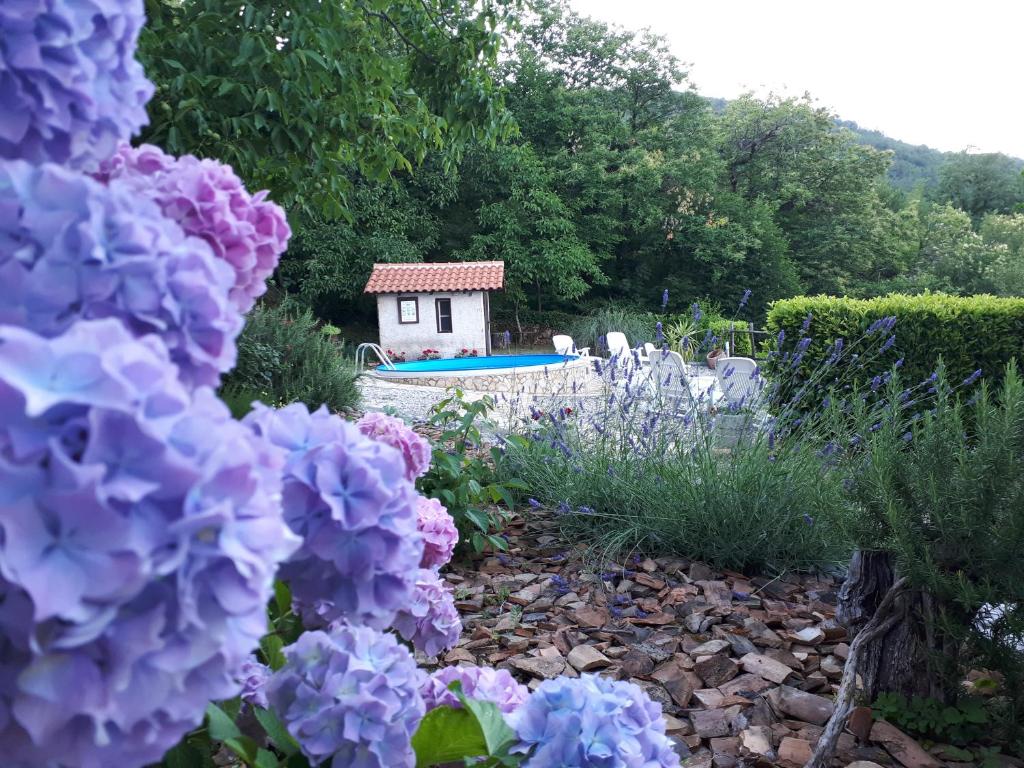 a garden with purple flowers and a small house at Kuća Za Odmor Mikleus in Lovran