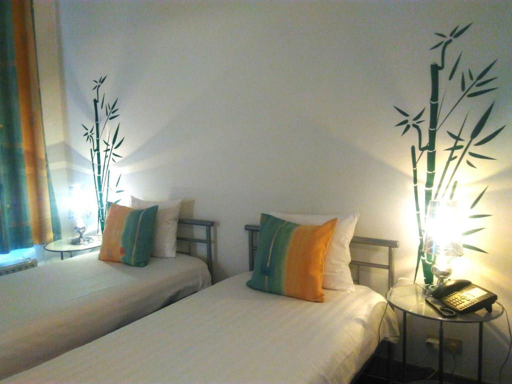 a bedroom with two beds and two tables with lamps at Eurotel in Liège