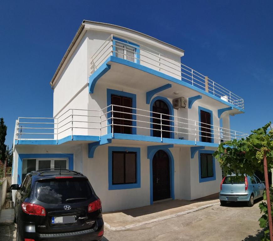 a white and blue house with cars parked in front at Matovic Apartments in Dobra Voda